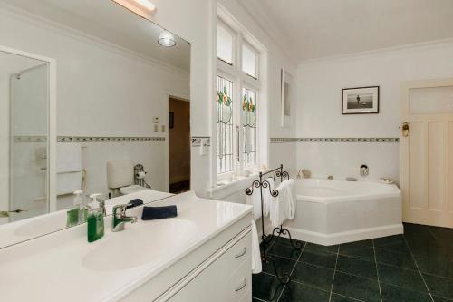 a white bathroom with a tub and a sink at The lookout Central in New Plymouth