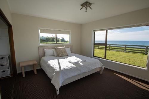 a bedroom with a bed with a view of the ocean at Wills On The Water Beachfront Apartment in Bell Block