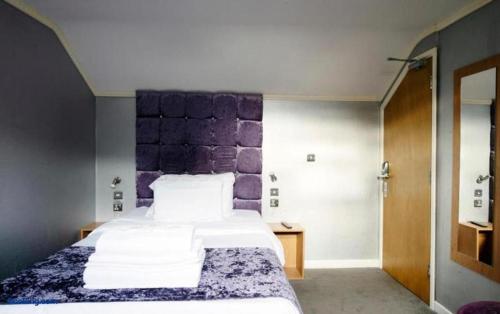 a bedroom with a large bed with a purple headboard at The Cozy Corner Inn in Newport