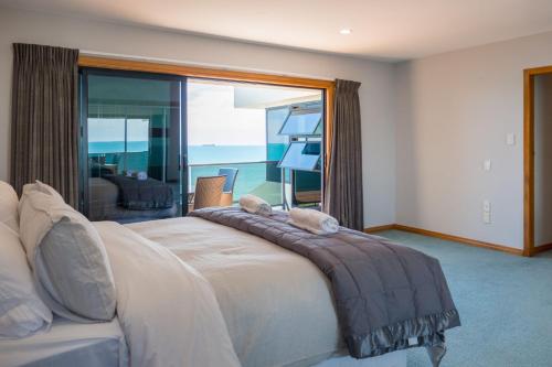 a bedroom with a bed with a view of the ocean at Waterfront On Woolcombe in New Plymouth