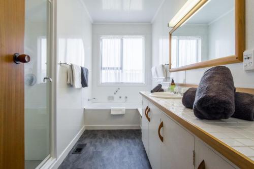 a white bathroom with a sink and a shower at Waterfront On Woolcombe in New Plymouth