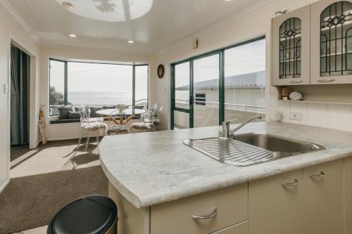 a kitchen with a sink and a living room at Wanaka Bay Waterfront in New Plymouth
