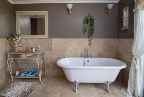 a bathroom with a white tub and a mirror at The Homestead Rural Family Retreat in Sentry Hill