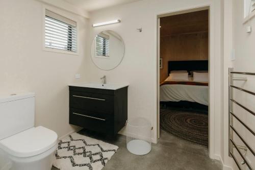 a bathroom with a sink and a toilet and a bed at Tremorne Stay in Inglewood