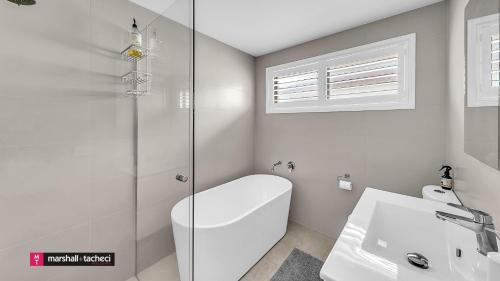 ein weißes Badezimmer mit Toilette und Waschbecken in der Unterkunft Horseshoe Beach House 4 Young Street, Bermagui in Bermagui