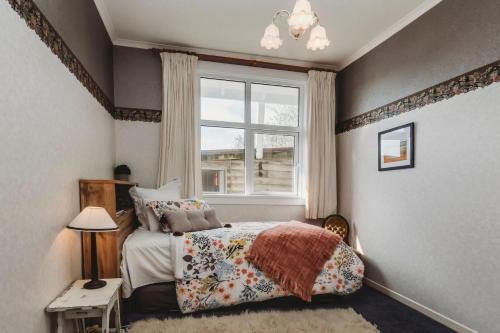 Schlafzimmer mit einem Bett und einem Fenster in der Unterkunft Timata Ora Sleeps 14 in New Plymouth