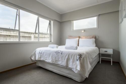 a bedroom with a large white bed with two windows at Sea Breeze On Belt By Coastal Walkway in New Plymouth