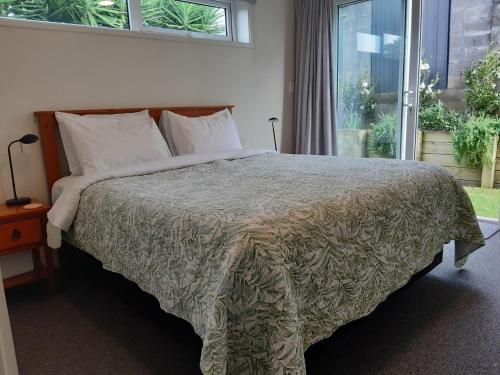 a bedroom with a large bed with a large window at By The Sea On Sackville Brand New Apartment in New Plymouth