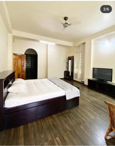 a bedroom with a large bed and a flat screen tv at Olive homestay in Kohīma