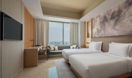 a hotel room with two beds and a flat screen tv at Alila Solo in Solo