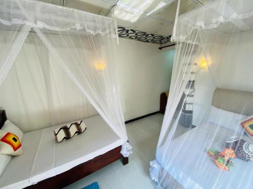 a bedroom with two beds with white curtains at Mellow Homestay in Ella