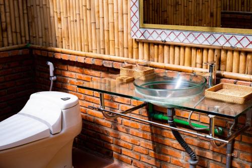 a bathroom with a toilet and a glass sink at Lumiere Family Village Dong Tac in Hiếu Xương