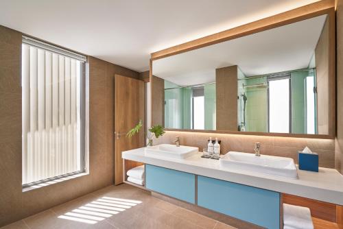 a bathroom with two sinks and a large mirror at IXORA Ho Tram By Fusion in Ho Tram