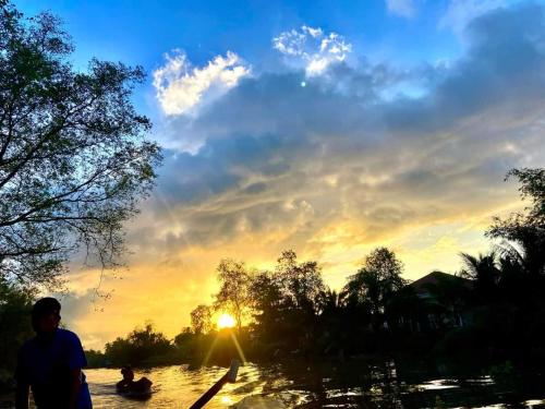 a person in a boat on a river at sunset at Green Village Mekong in Can Tho