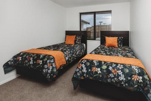 duas camas sentadas uma ao lado da outra num quarto em Bell Block Beauty Brand New em New Plymouth