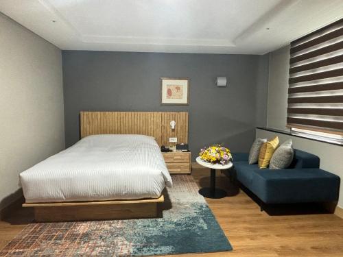 1 dormitorio con 1 cama y 1 sofá azul en Gumi Century Hotel, en Gumi