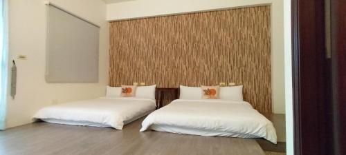 2 letti in una camera con lenzuola bianche di Redbean Guesthouse a Wujie