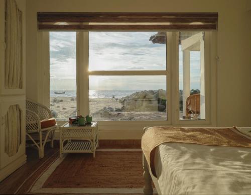 a bedroom with a view of the ocean from a window at Seclude Kerala, Beach House in Mararikulam