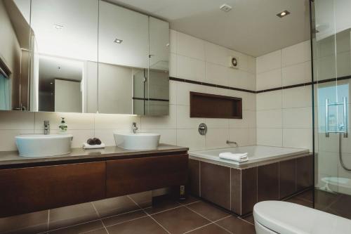 a bathroom with two sinks and a tub and a toilet at Liardet22 The Penthouse in New Plymouth