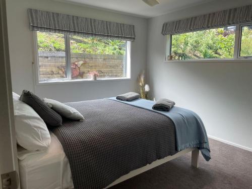 1 dormitorio con 1 cama y 2 ventanas en Seaviews On Shearer Oakura, en Oakura
