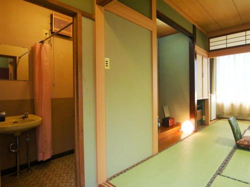 a bathroom with a mirror and a sink in a room at Guest Room Furusatomura Kogeikan in Omachi