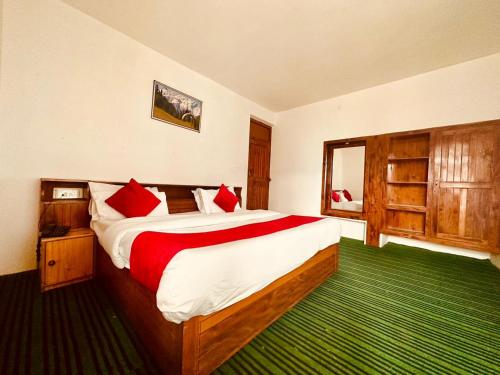 a bedroom with a large bed with red pillows at Hotel Alpine in Manāli