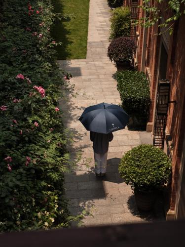 a person walking down a sidewalk with an umbrella at Capella Shanghai, Jian Ye Li in Shanghai