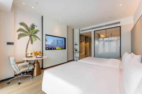 a hotel room with a large bed and a table at Kew Green Hotel Mianshuicheng Haikou in Haikou