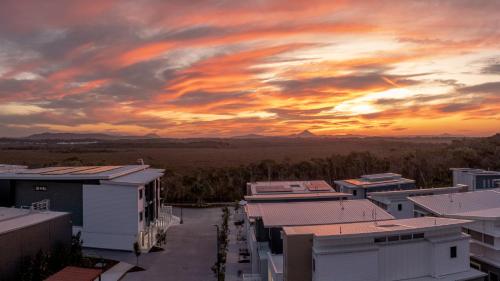 a sunset over a city with buildings and trees at Essence Peregian Beach Resort - Saltbush 5 Bedroom Luxury Home with Private Pool in Peregian Beach