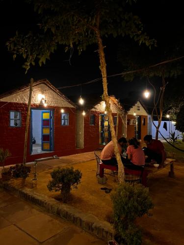 Backpackers Village Agra في آغْرا: مجموعة من الناس جالسين على مقاعد في الليل