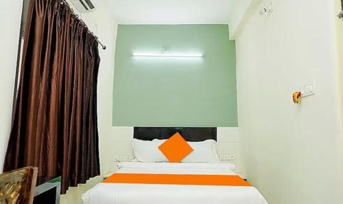 um quarto com uma cama com uma almofada laranja em FabHotel Ekamra Greens By Y Hotels em Bhubaneshwar