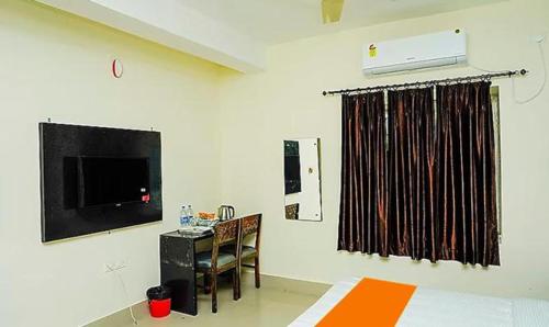 um quarto com uma cama, uma secretária e uma televisão em FabHotel Ekamra Greens By Y Hotels em Bhubaneshwar