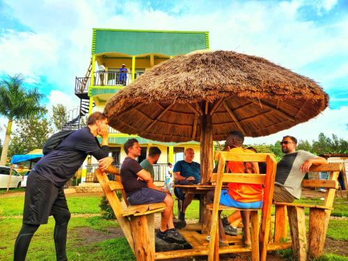 a group of people sitting at a table under an umbrella at Lights of kazinga orphanage and homestay in Rubirizi