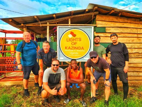 a group of men standing in front of a sign at Lights of kazinga orphanage and homestay in Rubirizi