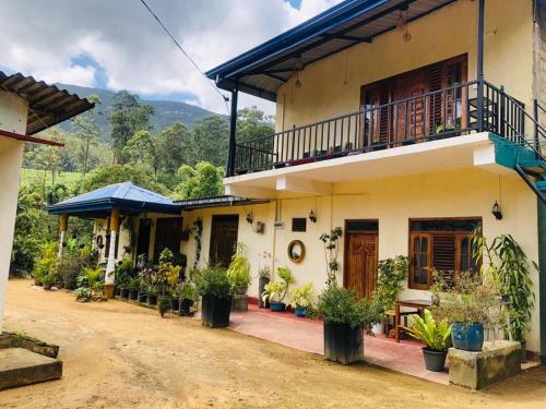 a house with a balcony and plants on a dirt road at Vegetable Garden House in Adams Peak