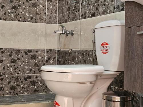 a white toilet in a bathroom with black tiles at غرووب وادي رم in Wadi Rum