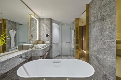 a bathroom with a white tub and two sinks at Grand HiLai Taipei in Taipei