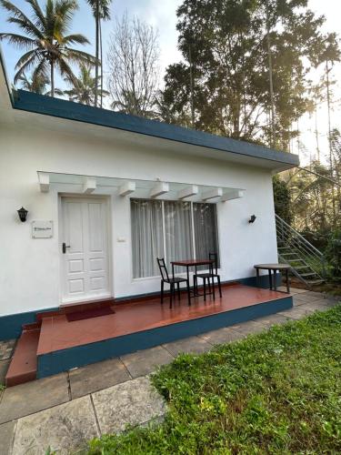 a house with a table and chairs on the porch at Silver Oak By Exuberance Stays (Independent Holiday Home) in Wayanad