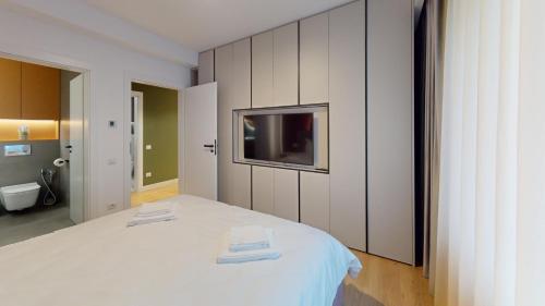 Schlafzimmer mit einem weißen Bett und einem TV an der Wand in der Unterkunft Quiet Luxury Home - home & office & car charging in Zalău