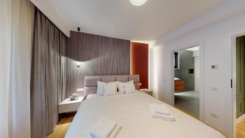 a bedroom with a large white bed and a bathroom at Quiet Luxury Home 1 - home & office in Zalău