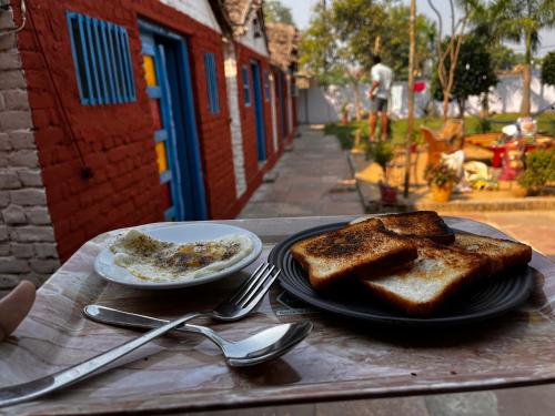 Backpackers Village Agra في آغْرا: طاولة مع خبز توست وصحن من الطعام عليها