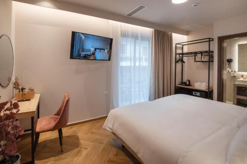 ein Hotelzimmer mit einem Bett, einem Schreibtisch und einem TV in der Unterkunft IRA - ΗΡΑ City Hotel in Kalamata