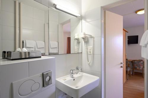 a white bathroom with a sink and a mirror at Olympia Hotel Zurich in Zürich