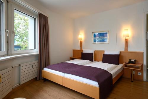 a bedroom with a large bed with two windows at Olympia Hotel Zurich in Zürich