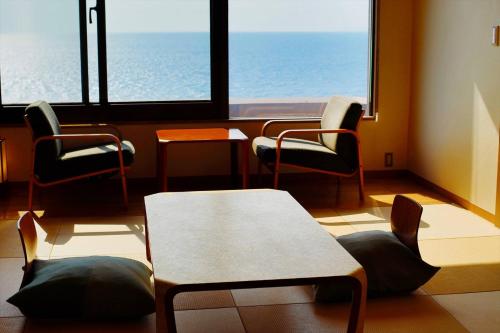 a waiting room with chairs and a table and windows at 海のほてる　いさば in Numazu