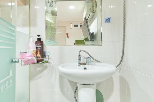 a white bathroom with a sink and a mirror at Snowflower Guesthouse in Seoul