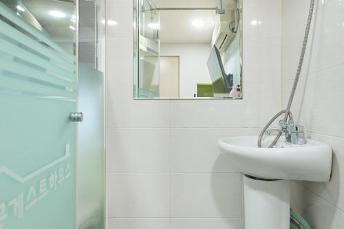 a white bathroom with a sink and a mirror at Snowflower Guesthouse in Seoul