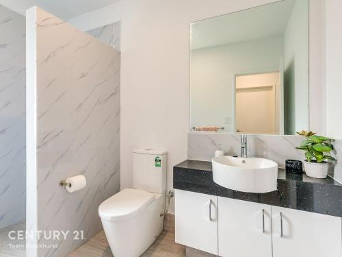 a white bathroom with a toilet and a sink at Hillside Merrifield Suites in Kelmscott