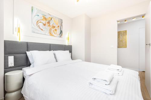 a white bedroom with a large bed with white sheets at Apartament Grzybowska Premium by Your Freedom in Warsaw