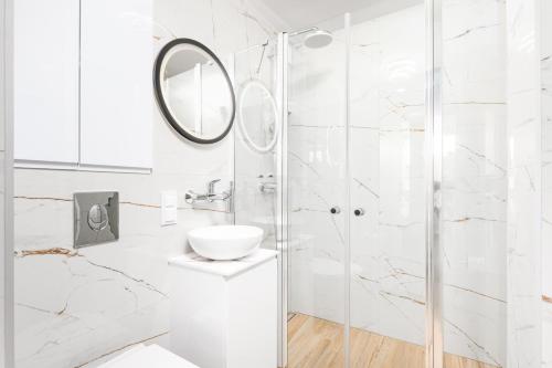 ein weißes Bad mit einer Dusche und einem Waschbecken in der Unterkunft Apartament Grzybowska Premium by Your Freedom in Warschau